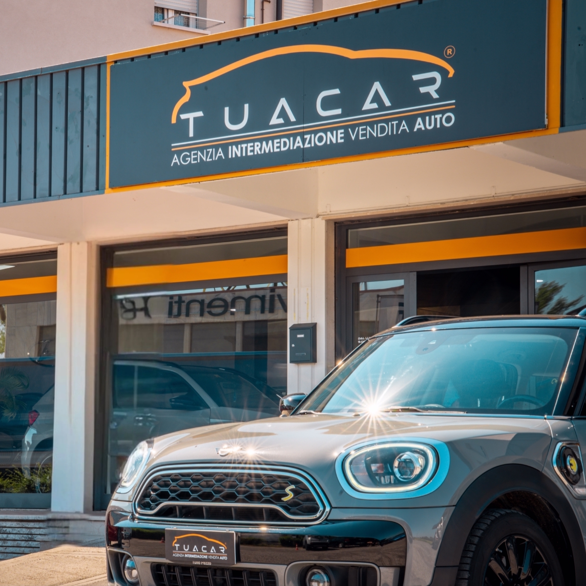 L'esterno di una sede TuaCar con una nuova Mini Cooper grigia parcheggiata di fronte